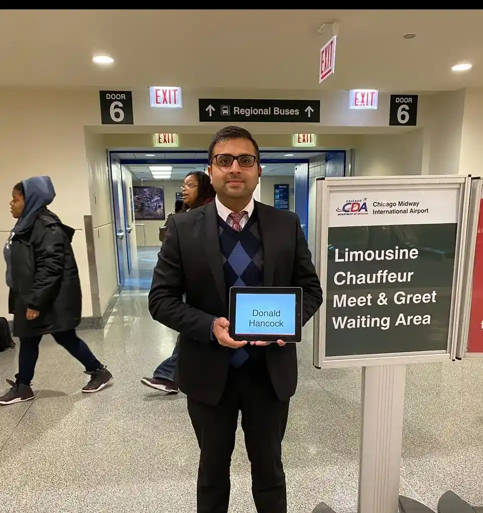 Chauffeur greeting passenger at airport with sign, offering luxury meet and greet transport service