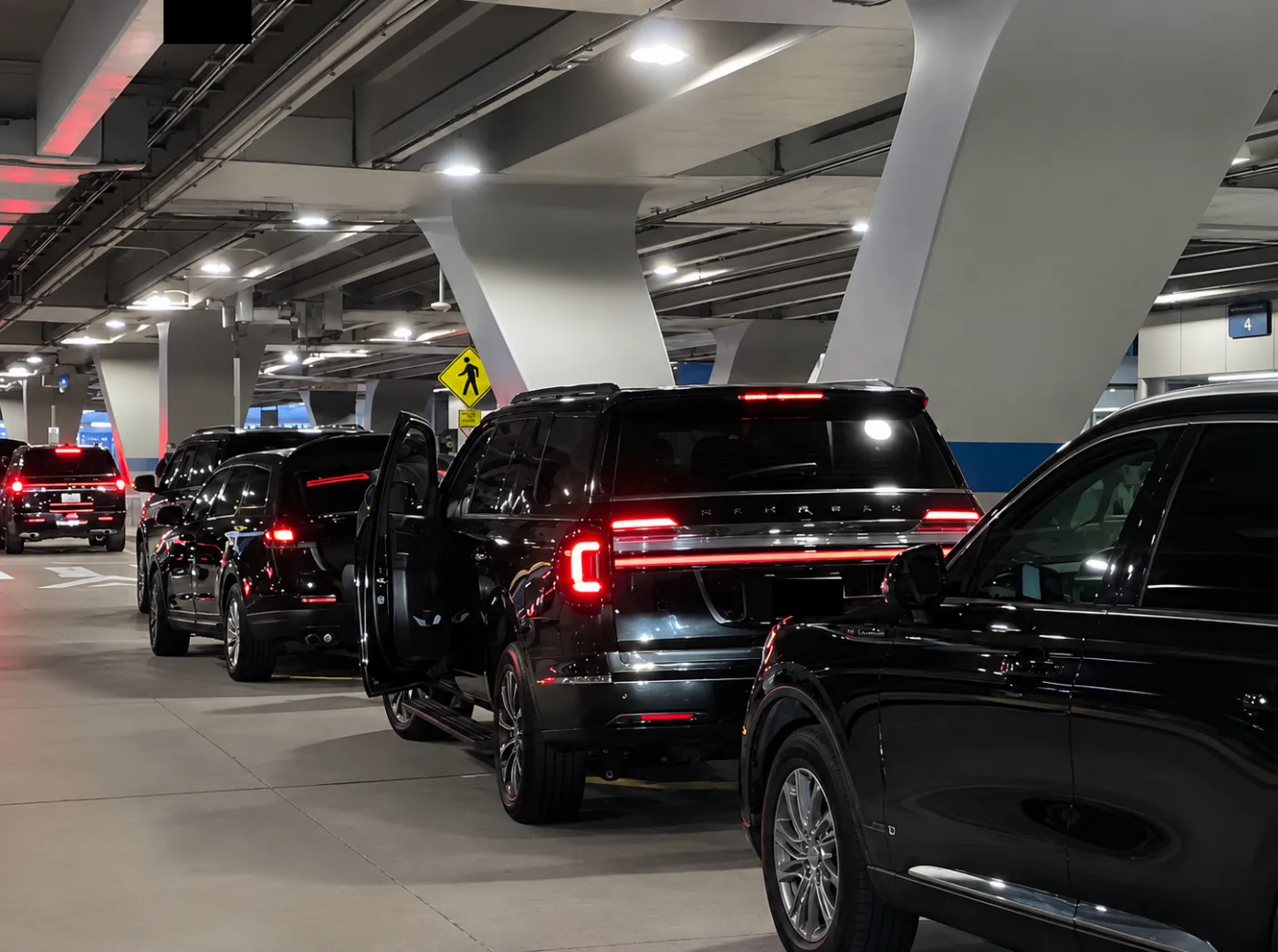 Black SUVs Lined Up Under Airport Lights
