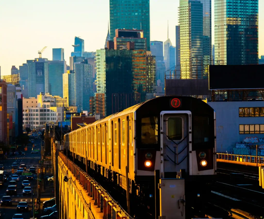 a-train-traveling-through-a-city-with-tall-buildings-in-queens